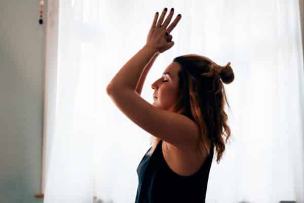 Close up image of a woman with hands clasped performing the sun salutation yoga pose.